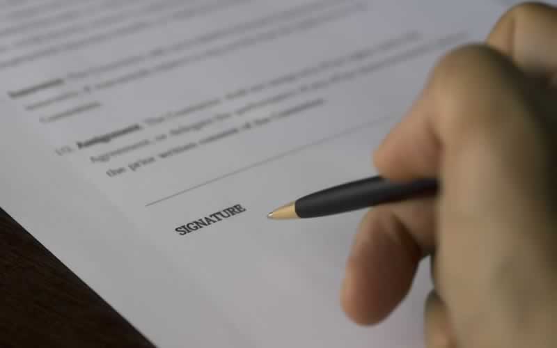 Photo of a hand signing a paper.